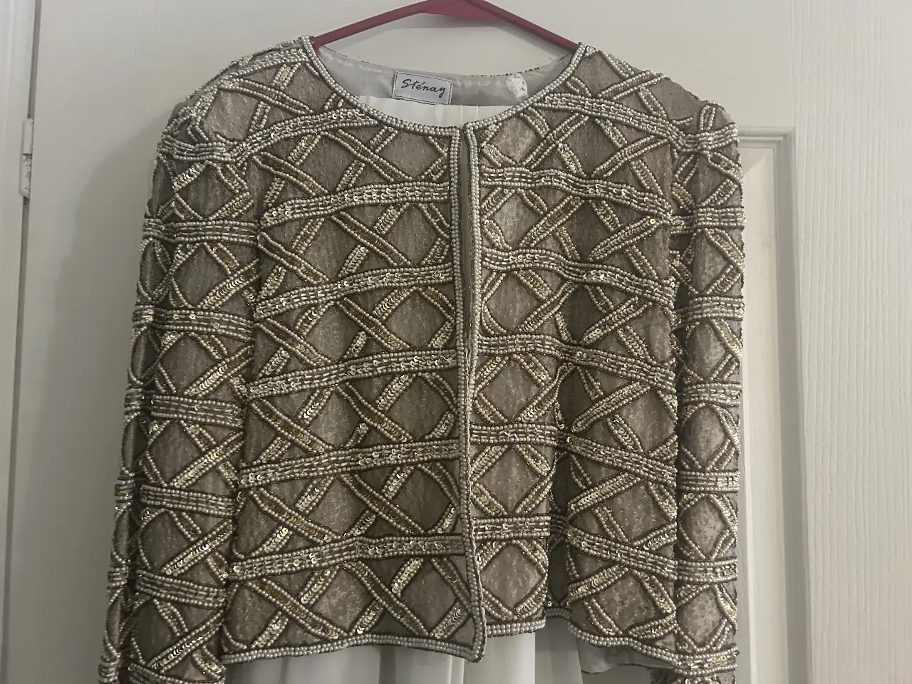 Chaqueta de fiesta Sténay con detalles bordados y lentejuelas doradasybpollera larga de crepé marfil. Ideal para eventos especiales y looks elegantes. Importado