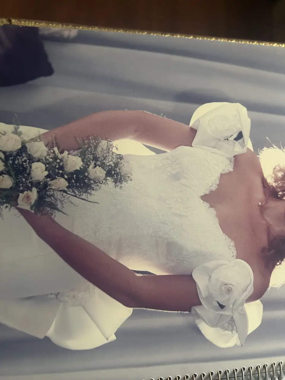 Vestido de novia blanco, con detalles de encaje y flores en los hombros. Corte elegante y cola larga. La cola es desmontable
