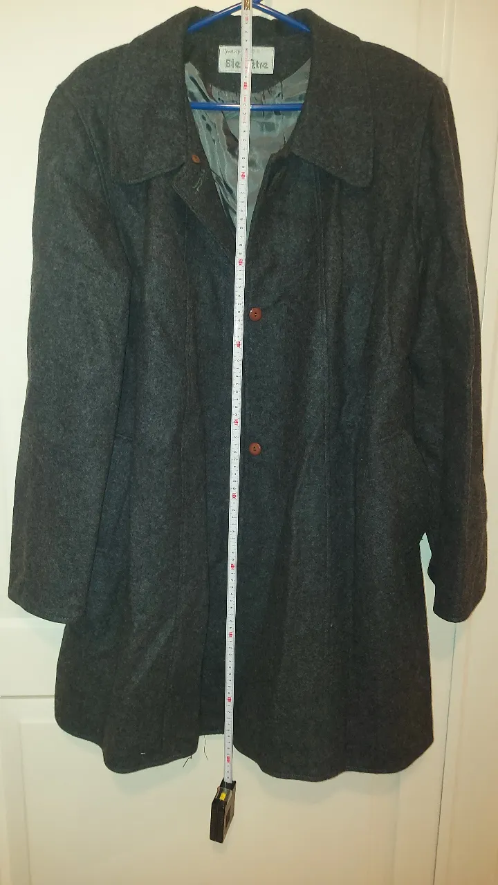 Abrigo de paño gris oscuro, ideal para el frío. Posee botones marrones y un corte clásico que lo hace versátil para diferentes ocasiones.