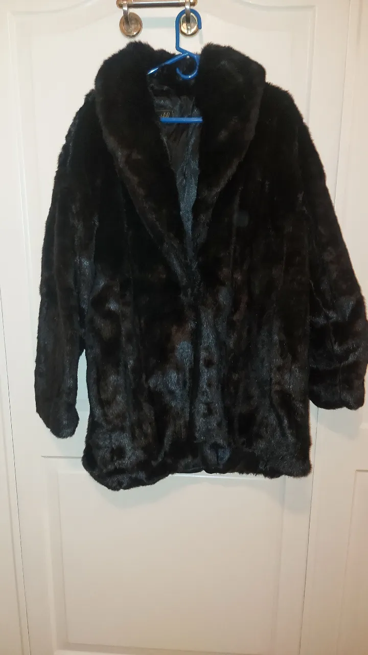 Abrigo de piel sintética negro, súper suave y calentito. Ideal para las noches frías o para darle un toque de glamour a tu outfit. Es un clásico que nunca pasa de moda.