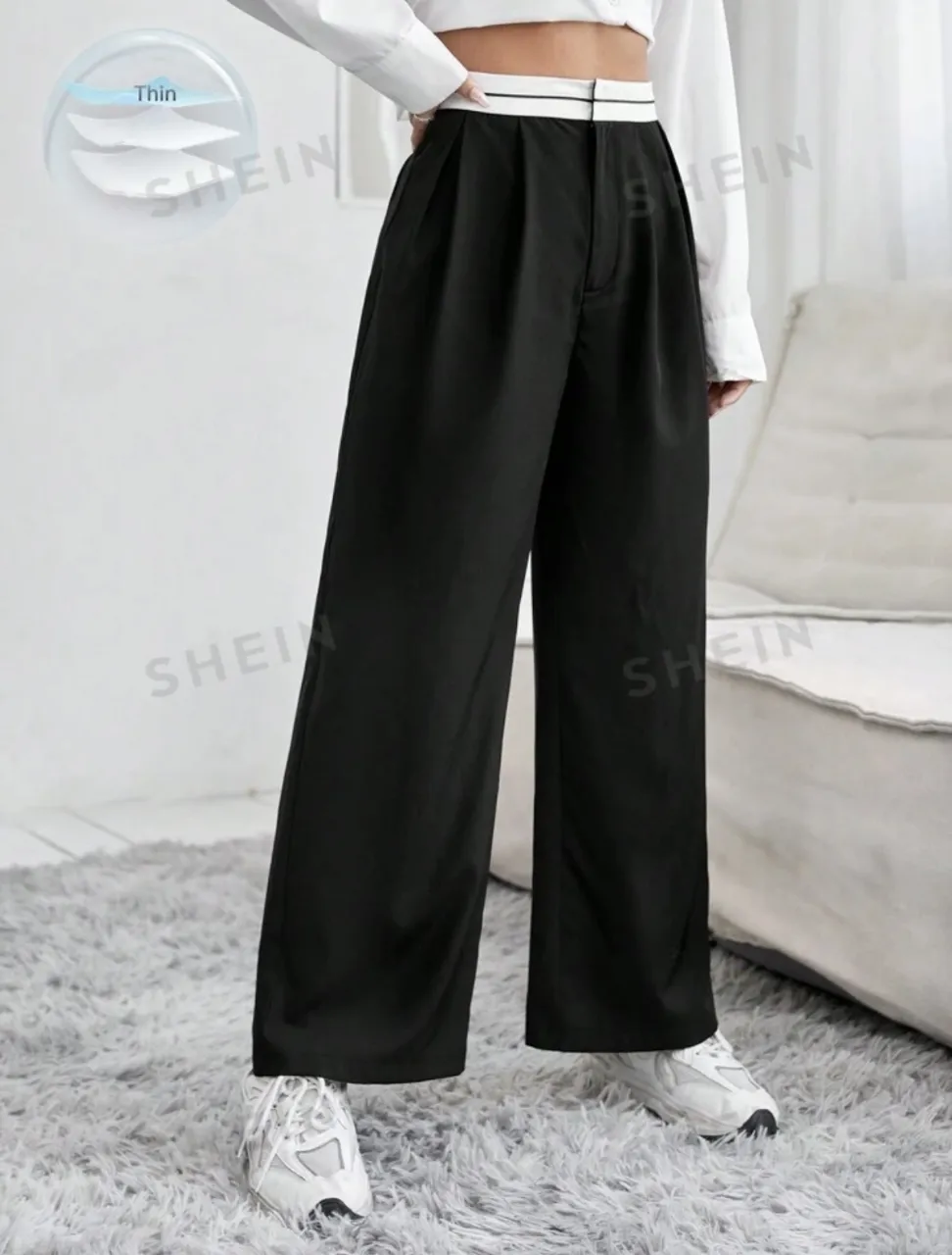 Pantalón negro de vestir con cintura blanca y dos líneas finas blancas. Posee pinzas en la parte delantera y un botón.