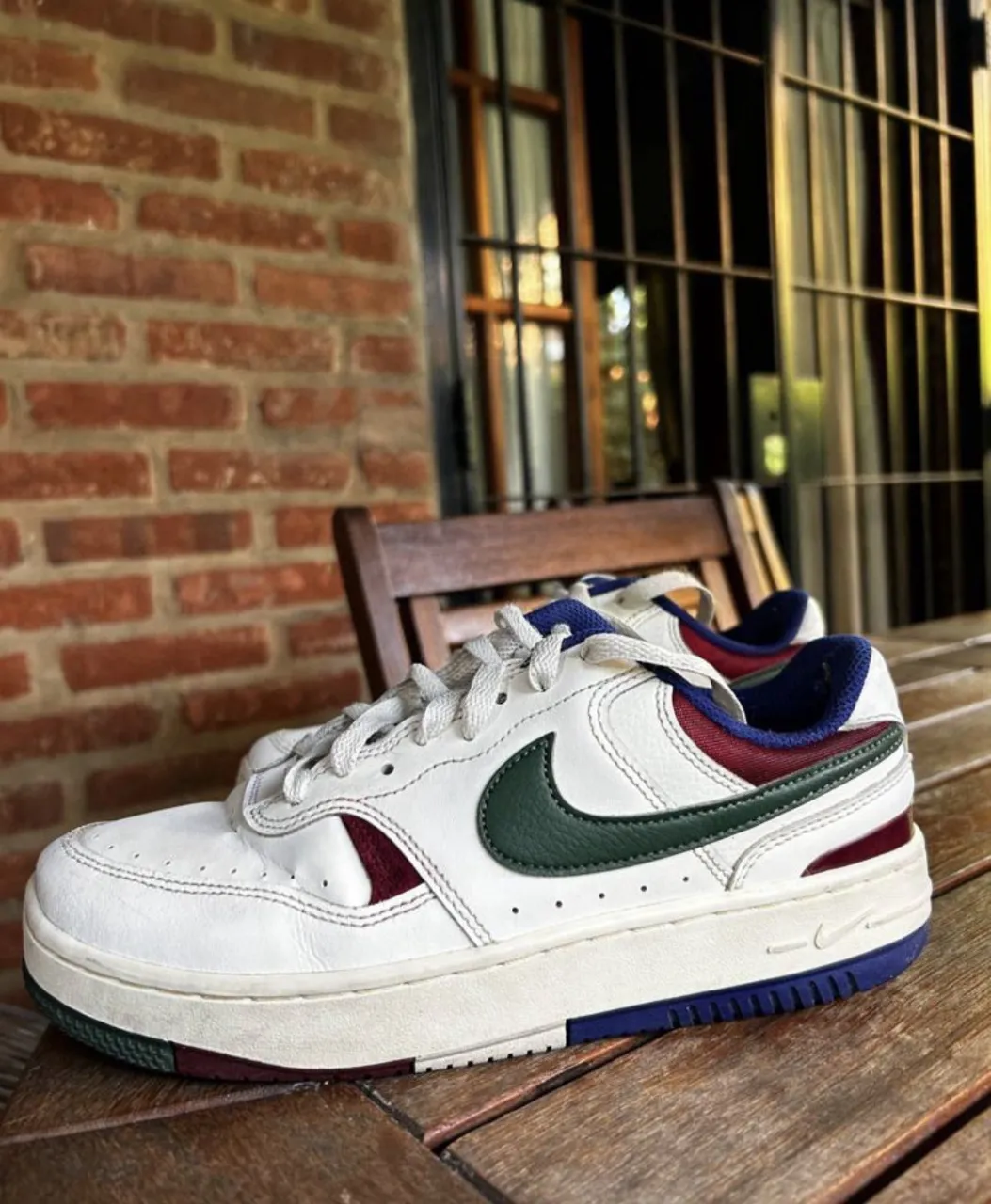 Zapatillas Nike blancas con detalles en verde, bordó y azul. Logo de Nike bordado en dorado en el talón.