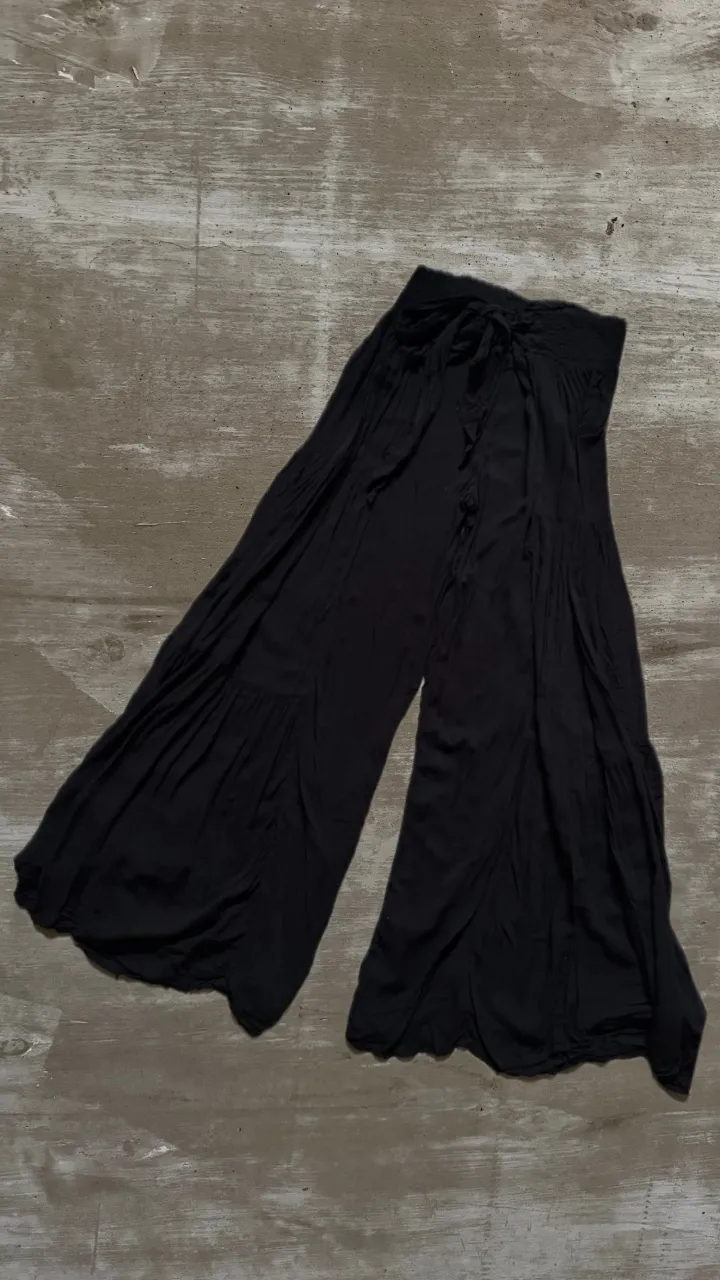 Pantalón de IndiaStyle negro de tela liviana con cintura elastizada y lazo para atar. Tiene un corte ancho y voluminoso, con detalles de frunces en las piernas.