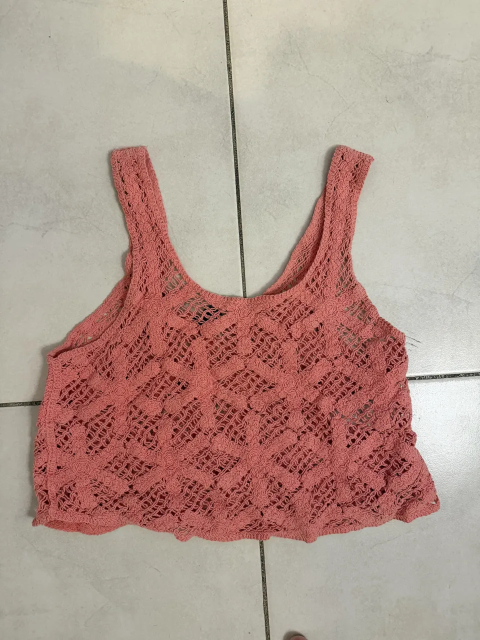 Musculosa tejida color coral con diseño de flores y rombos.