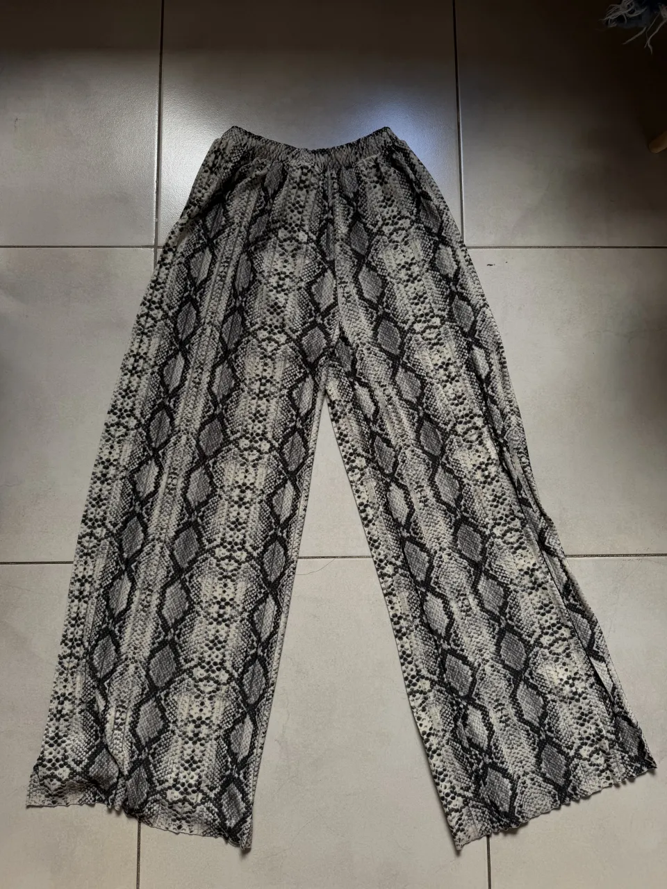 Pantalón estampado con diseño de serpiente en tonos grises y negros. Posee cintura elastizada y pierna ancha.