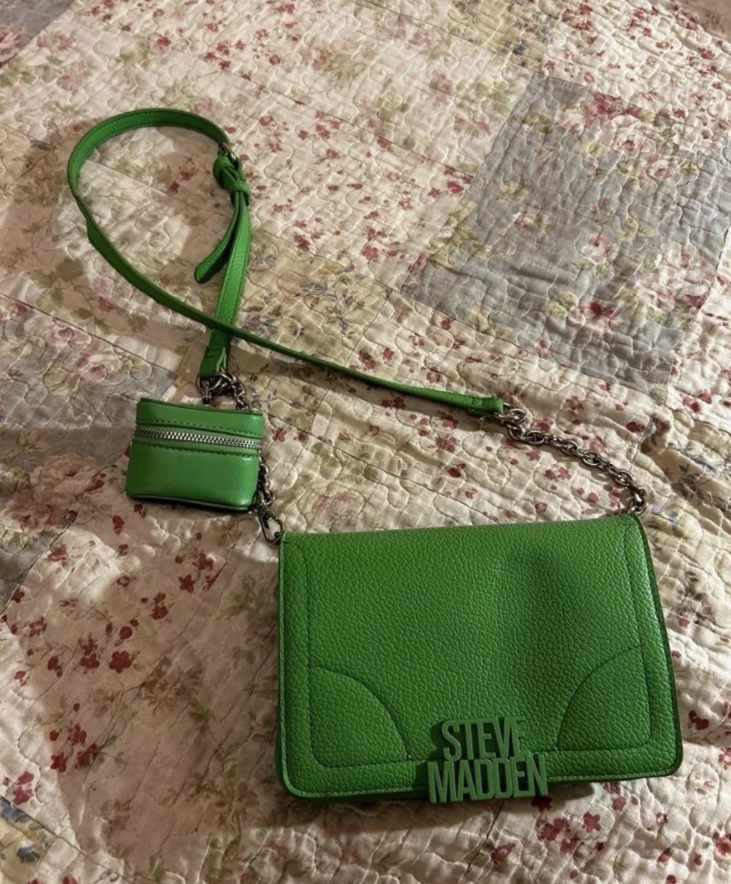Cartera verde de Steve Madden en la parte frontal. Incluye un pequeño monedero colgante con cierre. 