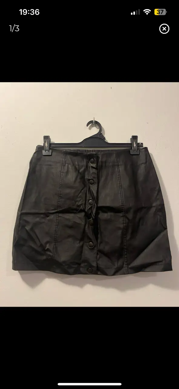 Minifalda de cuero sintético negra con botones delanteros. Talle L. Ideal para un look moderno y versátil.