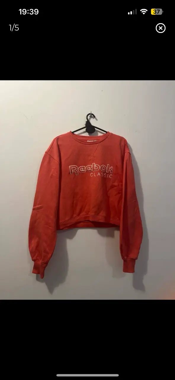 Buzo de cuello redondo Reebok Classic salmón/ coral, de algodón, con logo bordado en blanco. Ideal para un look casual y cómodo.