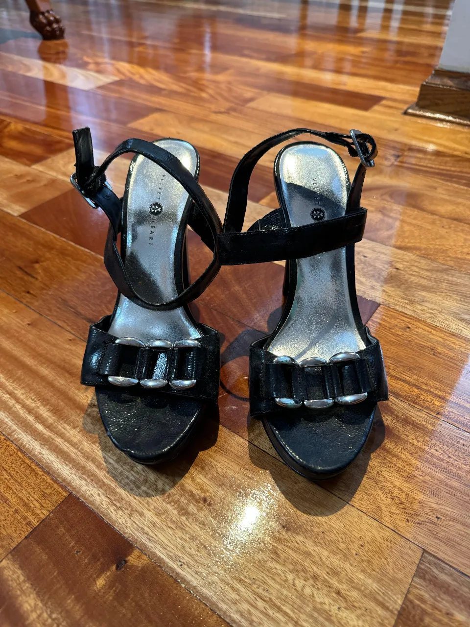 Sandalias de taco alto negras con detalles plateados. Ideales para fiestas y eventos.