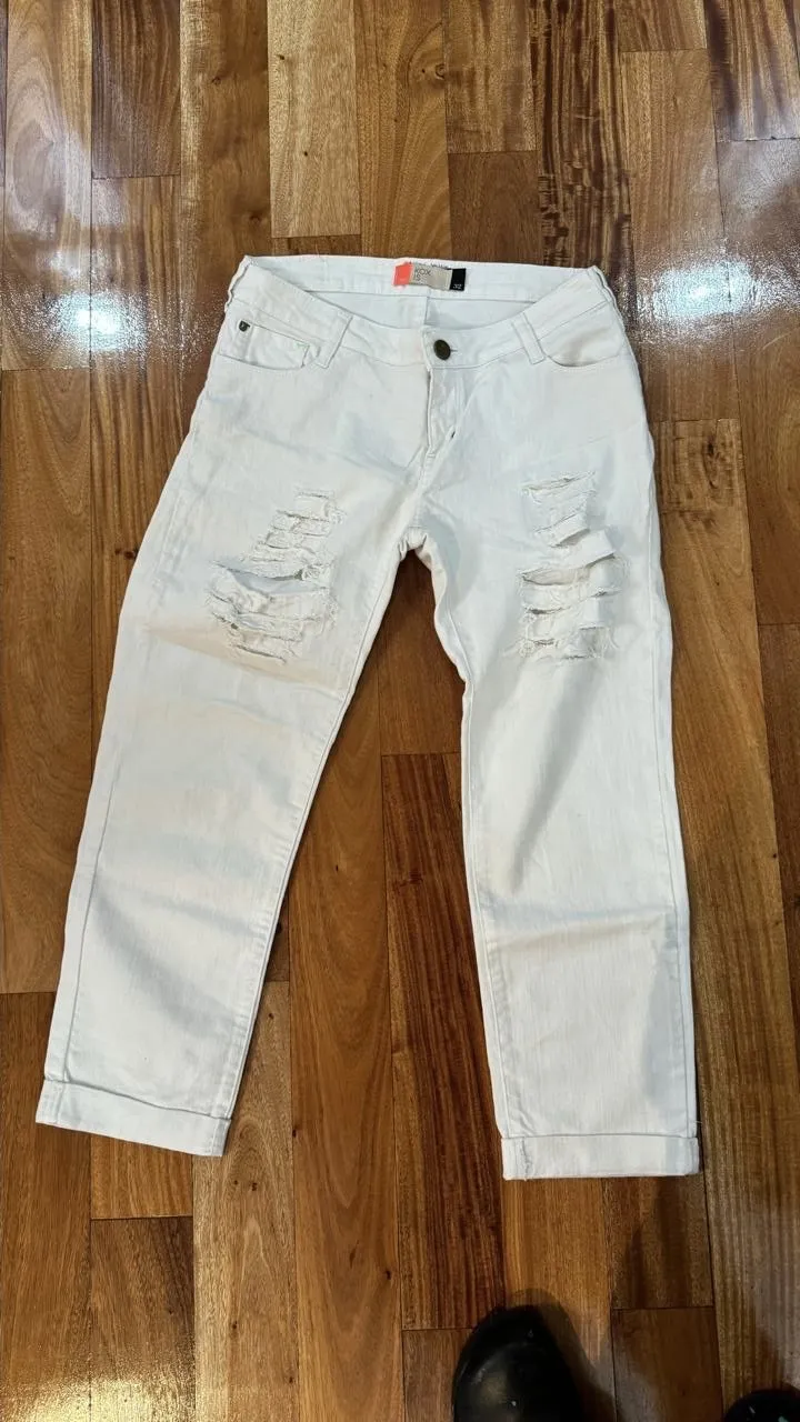 Jeans blancos con roturas en las rodillas, tiro medio y corte recto. Un clásico para un look casual y moderno.