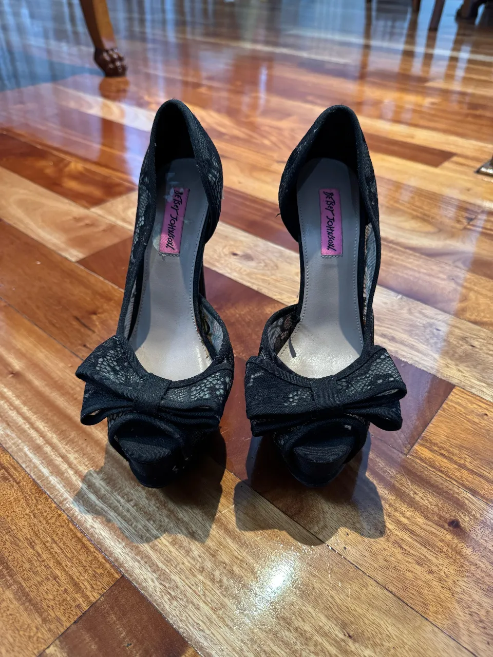 Elegantes tacos negros de la marca Betsey Johnson, con un diseño de encaje y moño en la punta. Ideales para fiestas y eventos especiales.
