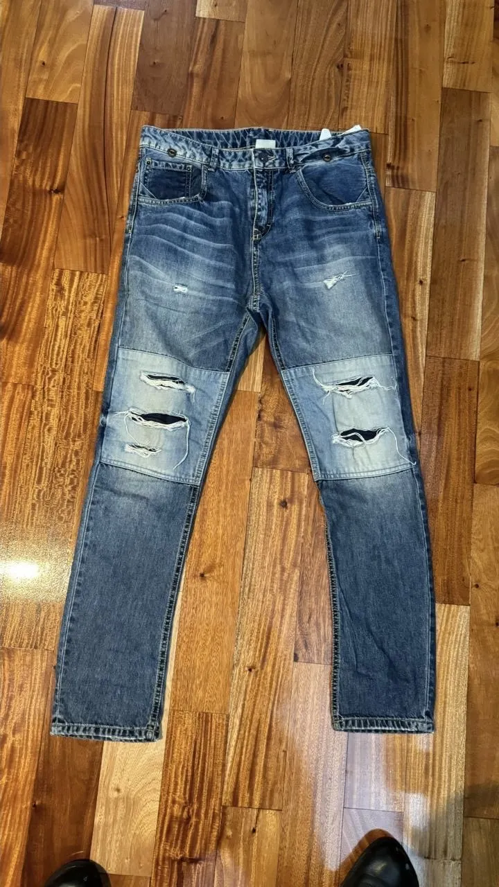 Jeans de hombre, azul, con roturas en las rodillas y parches. Tiro medio, corte recto.