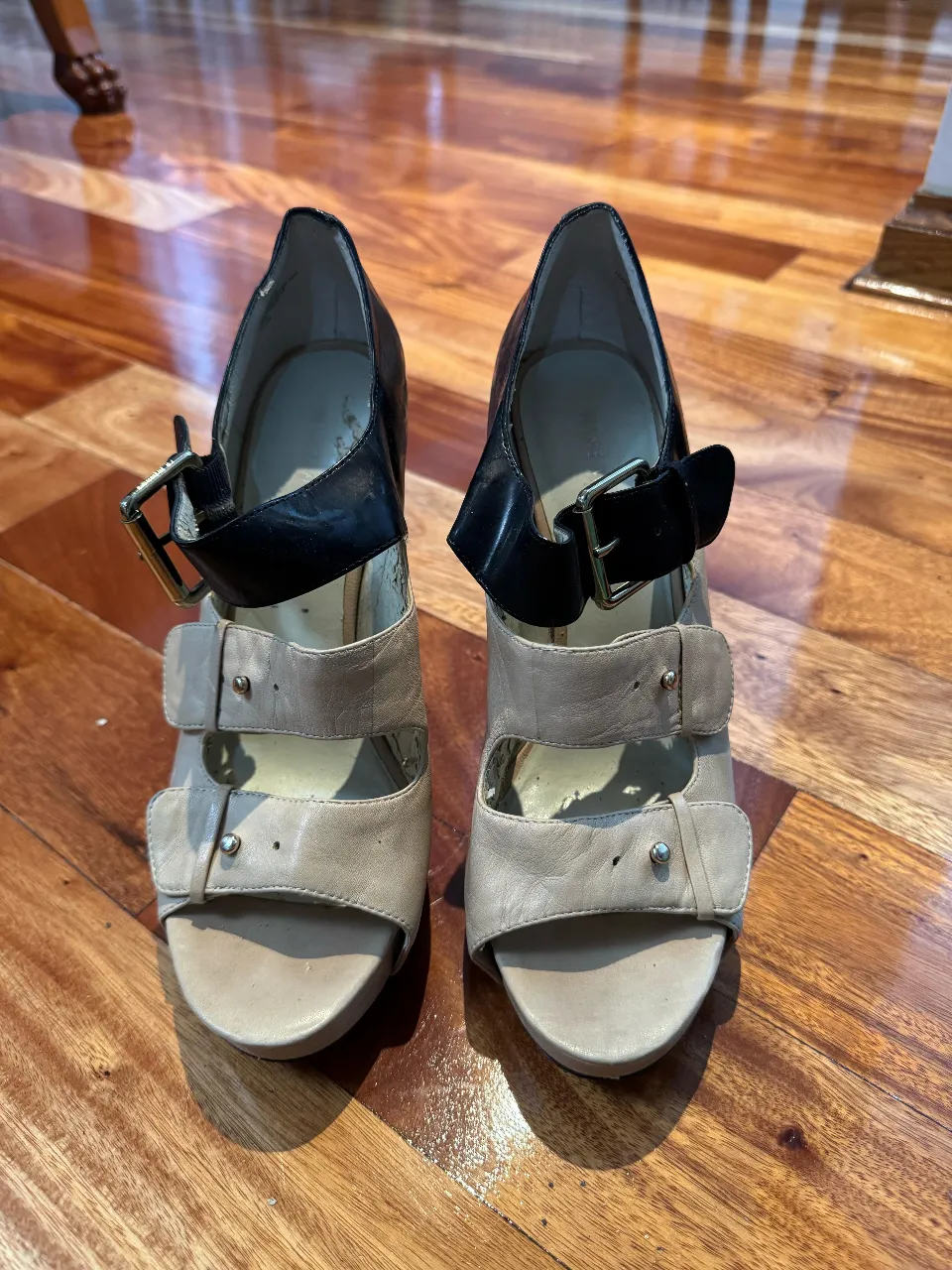 Sandalias de taco alto con detalles en cuero negro y beige. Diseño elegante y moderno, ideales para eventos especiales.