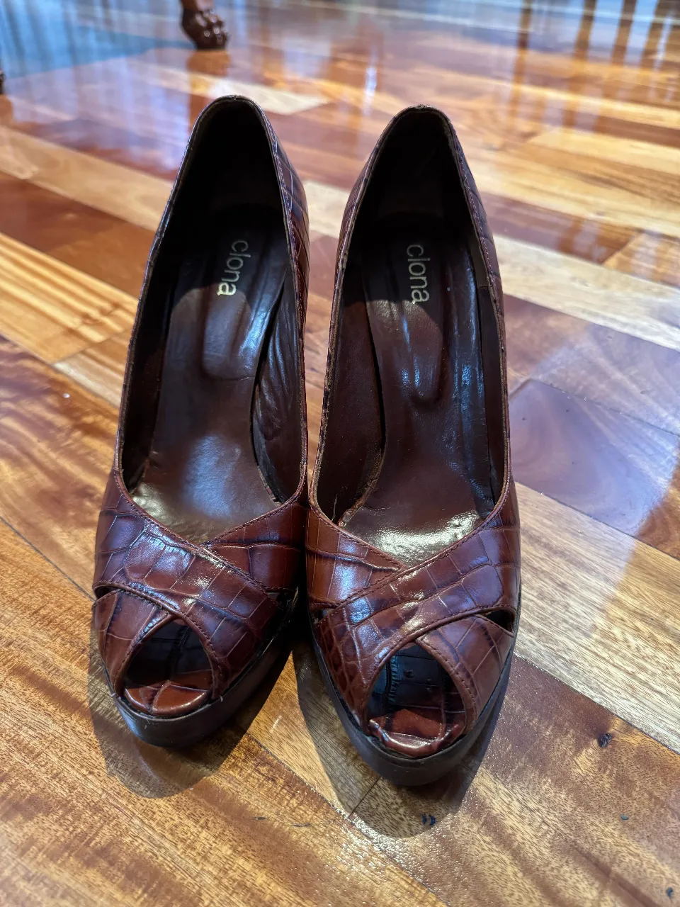 Elegantes tacos marrones de la marca Clona, con diseño de piel de cocodrilo y punta abierta. Ideales para eventos formales o salidas nocturnas.