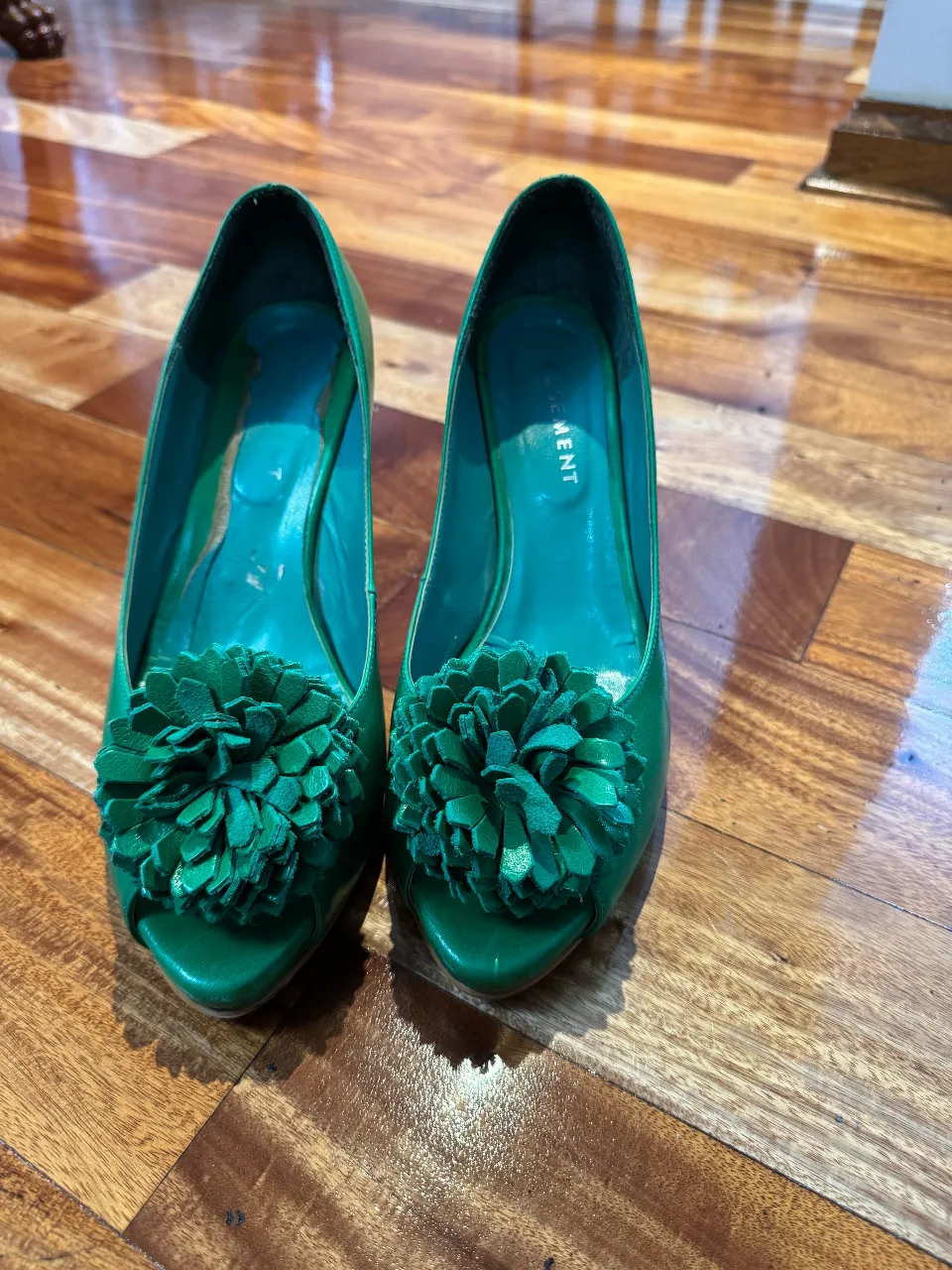 Elegantes zapatos de tacón verde con detalle floral. Ideales para fiestas y eventos especiales.