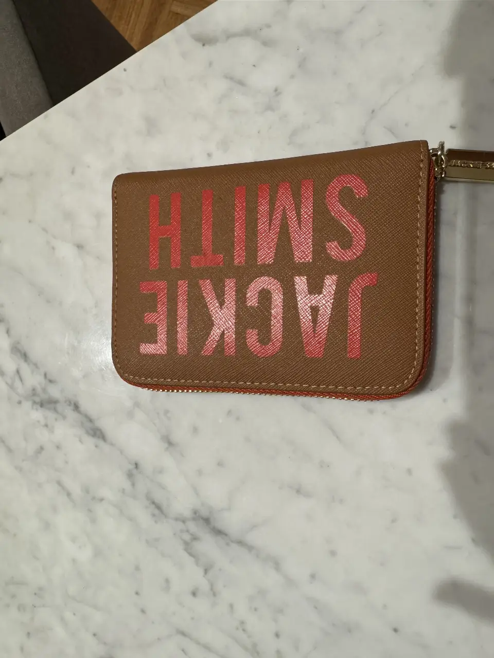 Billetera Jackie Smith de cuero marrón con detalles en naranja.Diseño con cierre y espacio para tarjetas y billetes. Ideal para organizar tus pertenencias con estilo. Casi nueva del mes de enero. Tiene dos manchitas mínimas en la letra T.