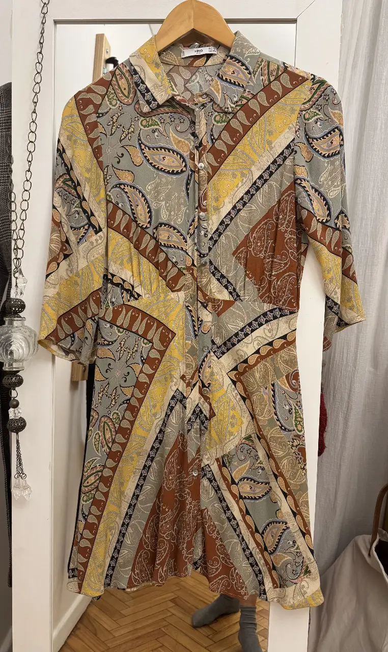 Vestido midi con estampado paisley en tonos amarillos, marrones y grises. Corte evasé, manga 3/4 y cuello camisero. Ideal para un look retro y con estilo. Marca Mango