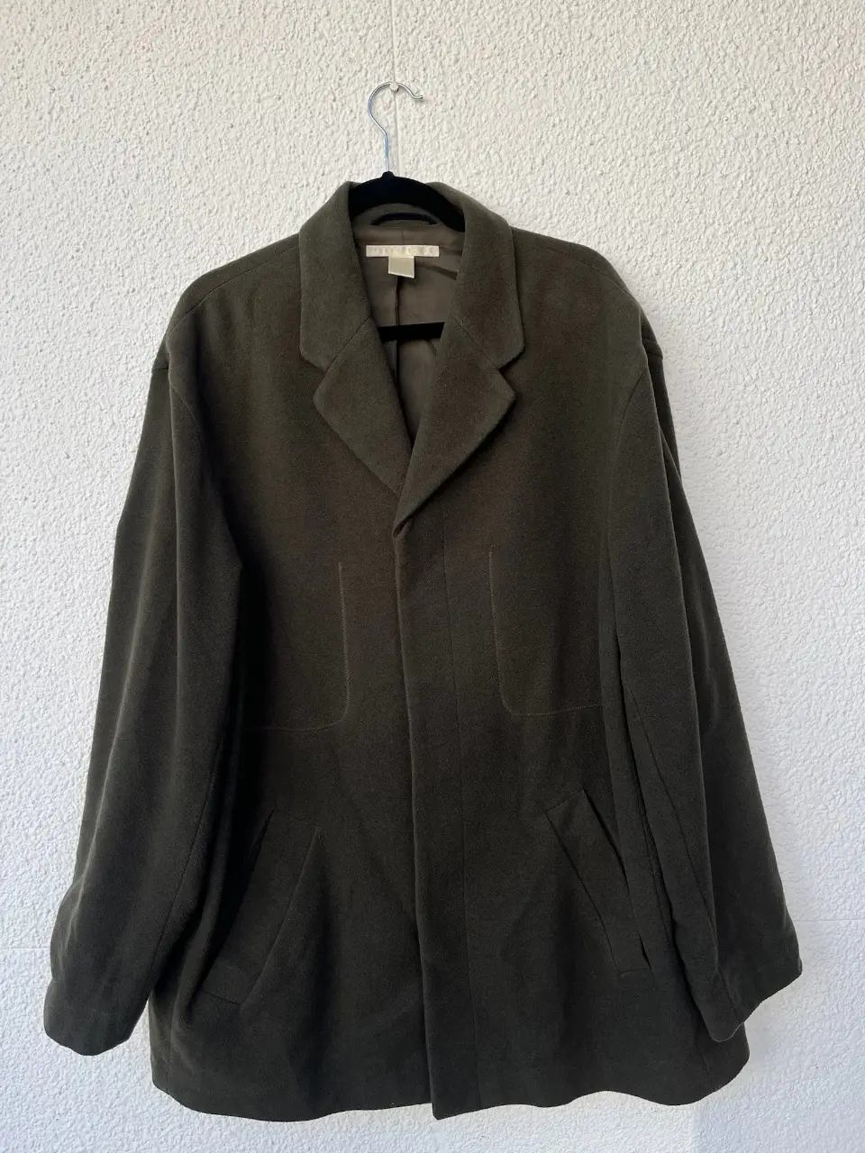 Sobretodo de hombre color verde oscuro, con solapas clásicas y bolsillos delanteros. Ideal para un look elegante y abrigado en invierno.