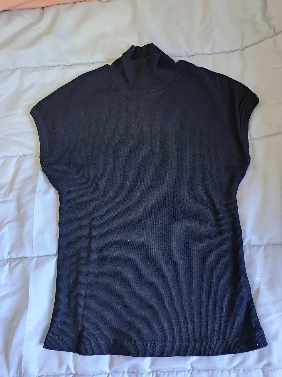 Remera negra de cuello alto y mangas cortas. Tejido acanalado.