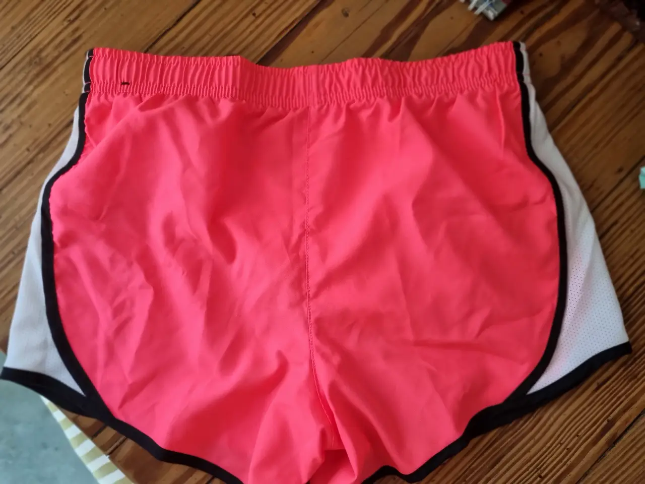 Short deportivo de mujer, color rosa chicle con detalles en blanco y negro. Ideal para running y entrenamientos.