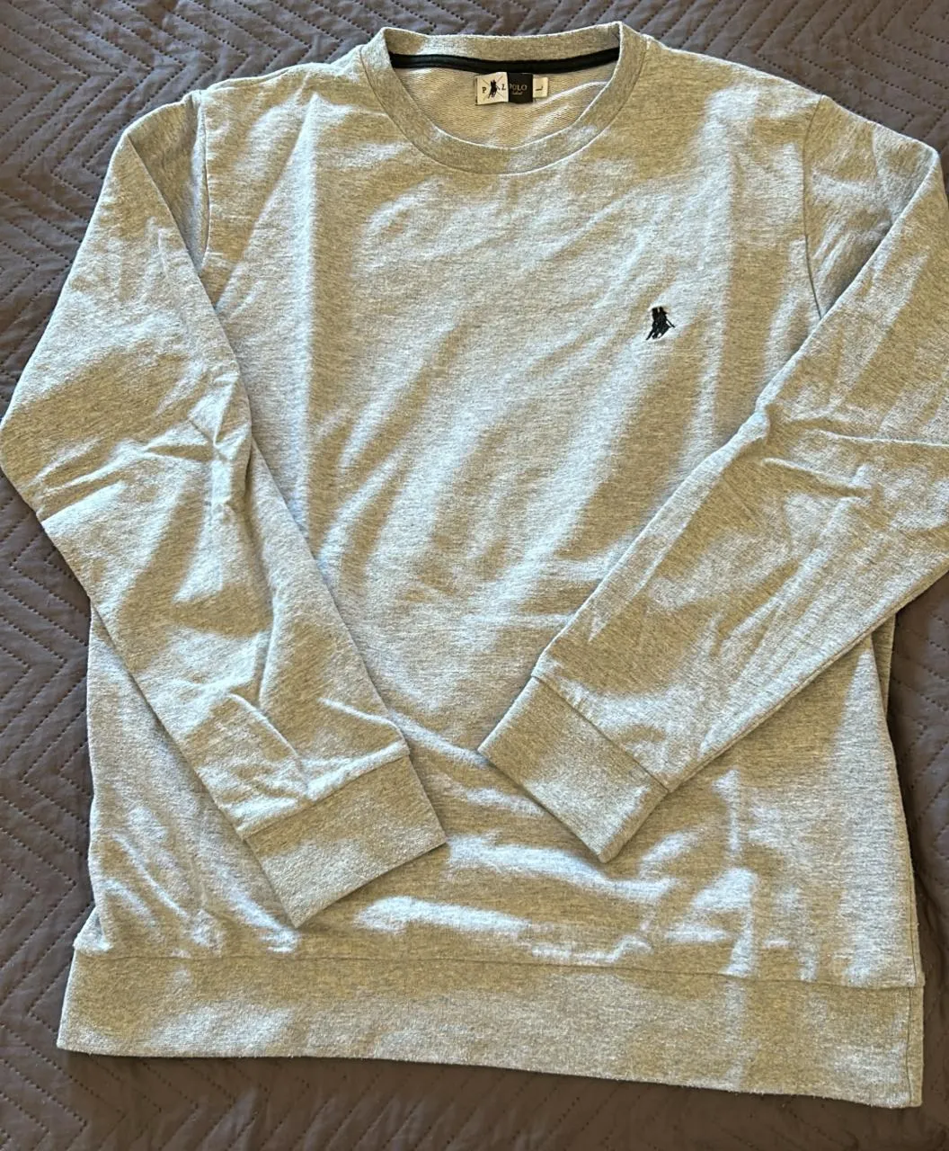 Buzo de algodón gris con un pequeño bordado en el frente. Cuello redondo y mangas largas. buzo fino. 