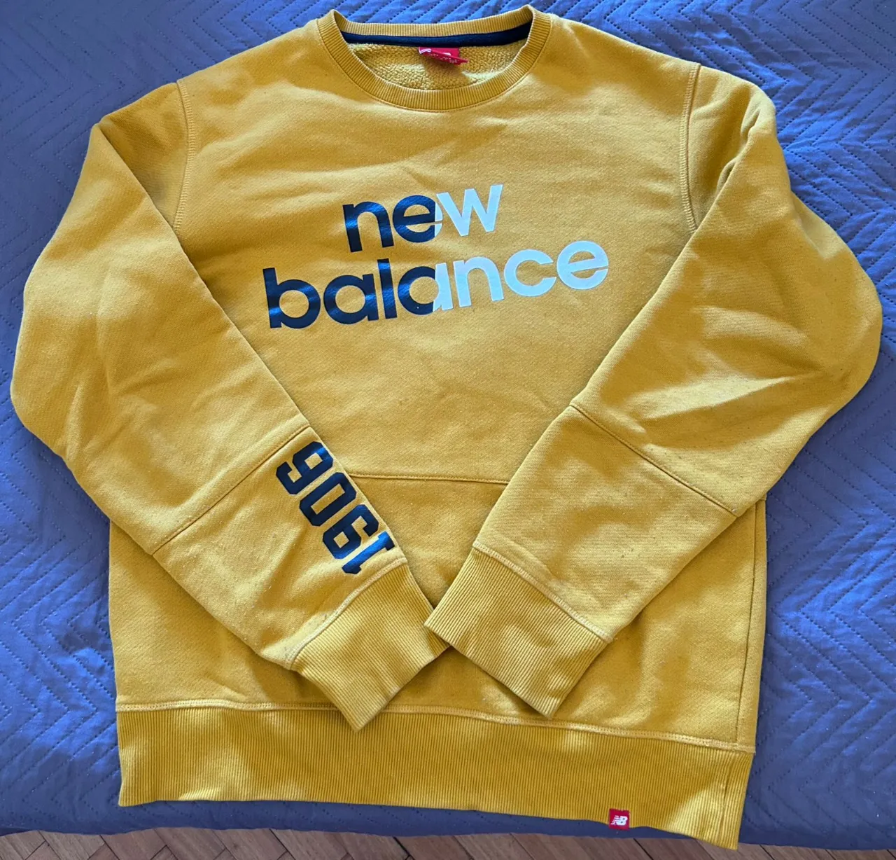 Buzo amarillo con estampa "new balance" en el frente. Detalle "906" en la manga izquierda.