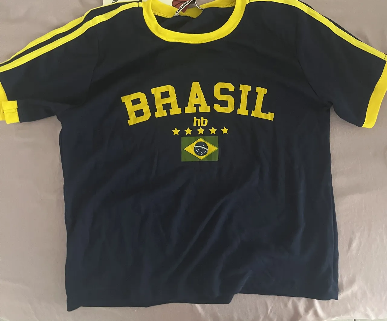 Remera deportiva azul marino con estampa "BRASIL" en amarillo y detalles de la bandera de Brasil. Ideal para los fanáticos del fútbol o para lucir un look deportivo y canchero.