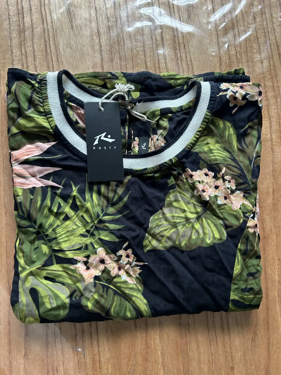 Blusa de mujer con estampado tropical, mangas cortas y cuello redondo con detalle en blanco. Ideal para un look fresco y casual.