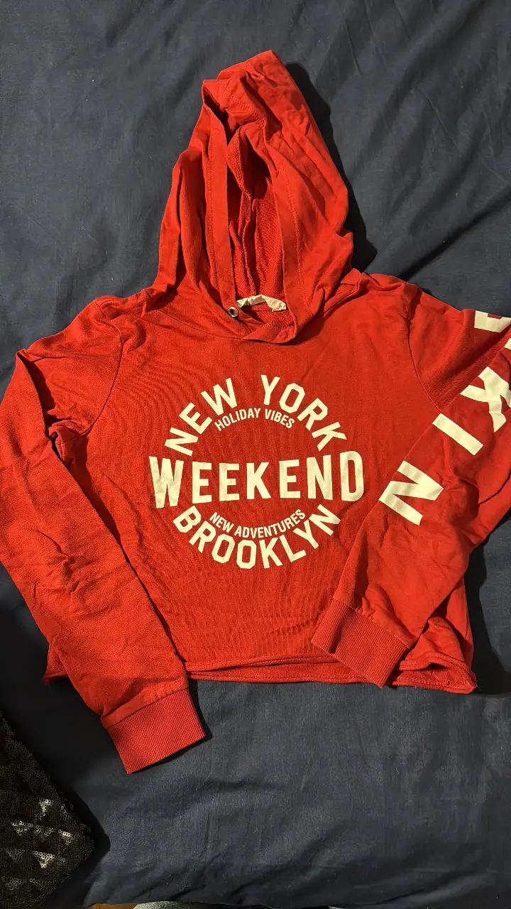Buzo canguro rojo con capucha y estampado "NEW YORK WEEKEND BROOKLYN". Ideal para un look casual y urbano.