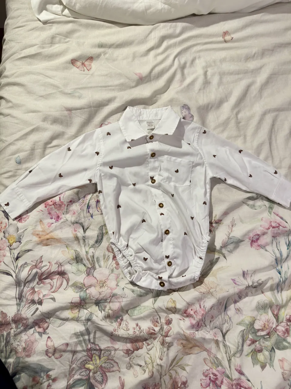 Body de bebé blanco con estampa de mariposas marrones. Manga larga y cuello de camisa. Ideal para los días de primavera y verano.