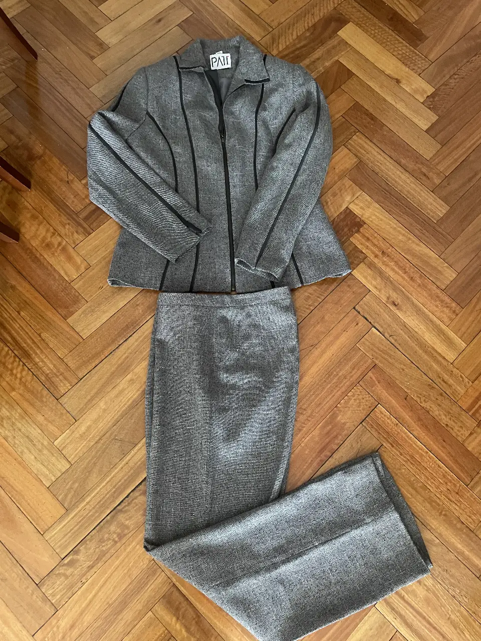 Conjunto de dos piezas de mujer, estilo sastrero. Incluye un blazer con cierre y detalles en negro, y un pantalón a juego. Ideal para un look formal o de trabajo.