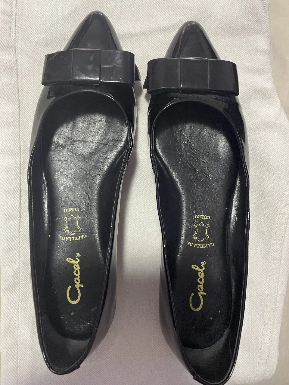 Ballerinas negras de charol con moño en la punta. Suela de goma con detalle dorado en el talón. Marca Gracel.