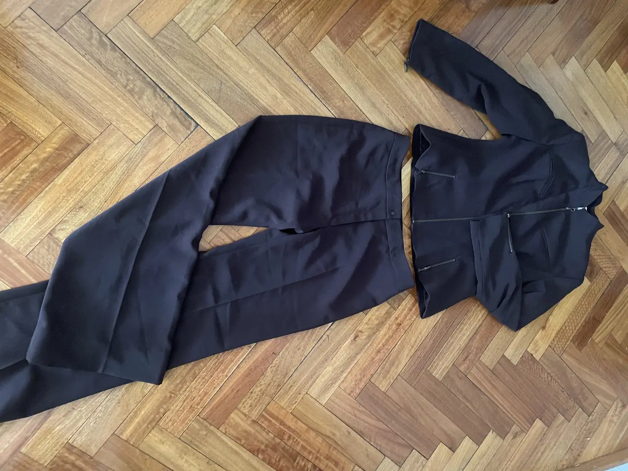 Traje sastrero de dos piezas color marrón oscuro. Incluye pantalón de corte recto y blazer con cierre frontal y bolsillos. Ideal para un look formal y elegante.