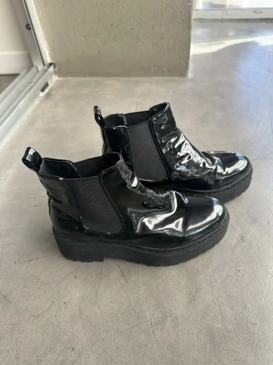 Botines negros de charol con plataforma. Tienen un diseño elegante y moderno, ideales para completar cualquier look.