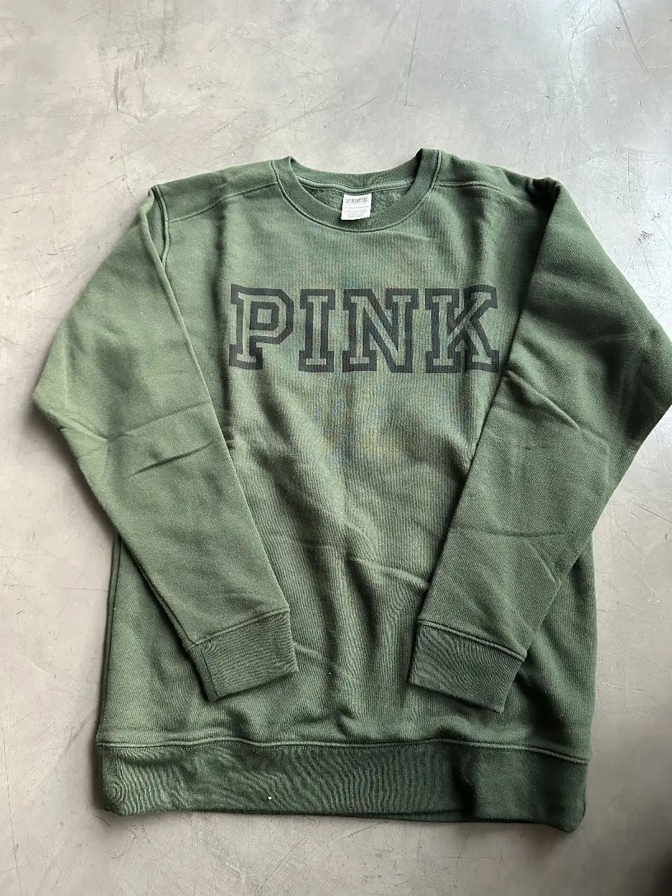 Buzo de cuello redondo de la marca PINK, color verde oscuro con estampado "PINK" en el frente. Ideal para un look casual y cómodo.