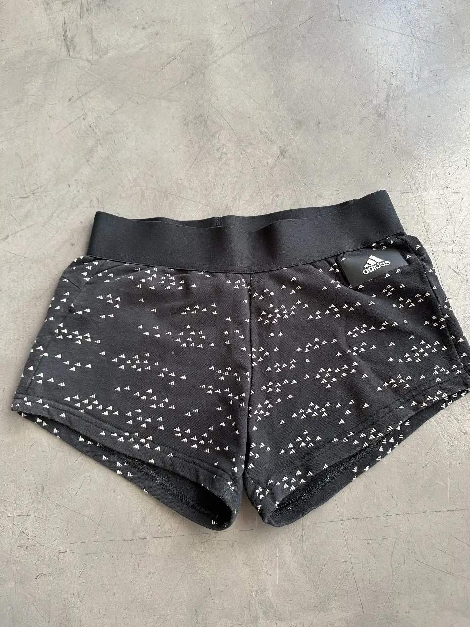 Short deportivo Adidas negro con estampado.  Talle XS, ideal para actividades físicas o uso casual. Cuenta con cintura elastizada y logo de la marca.