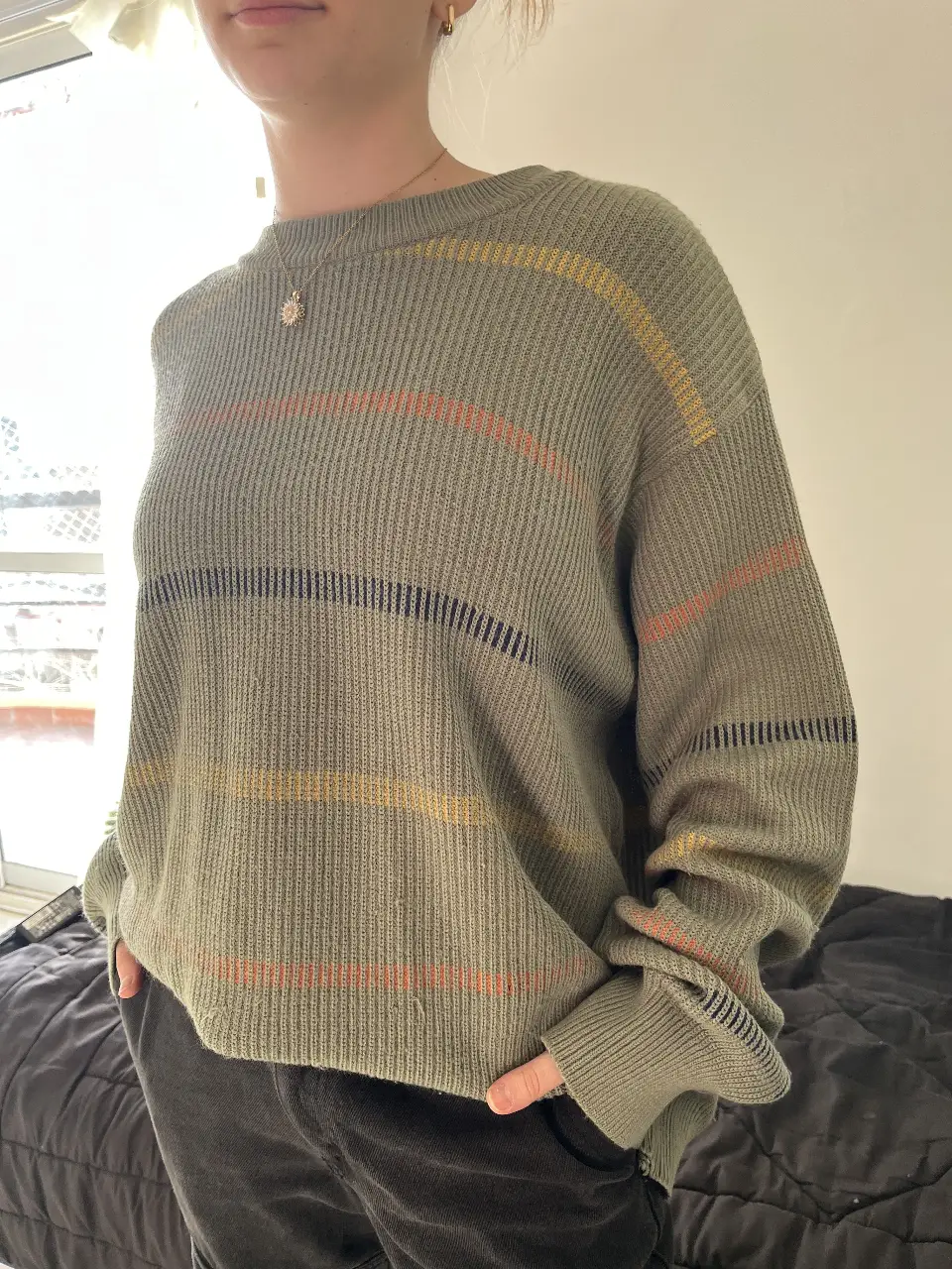 Sweater de punto grueso en color verde con rayas horizontales en amarillo, naranja y negro. Ideal para un look casual y abrigado.