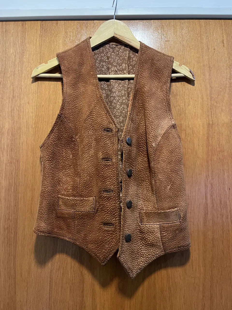 Chaleco de cuero marrón con textura, estilo vintage. Posee botones y bolsillos delanteros. Ideal para un look casual con un toque retro.