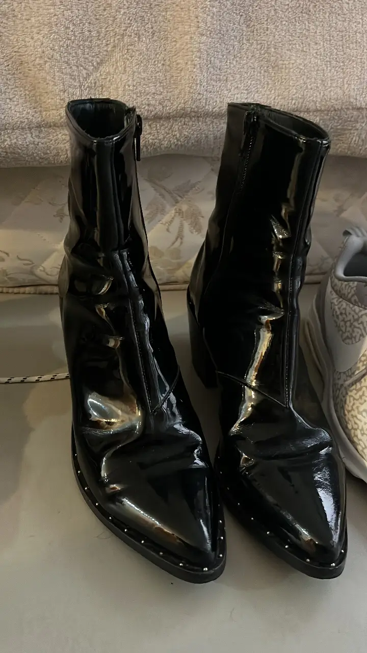 Botines de mujer negros de charol con detalles de tachas en la suela. Diseño elegante y moderno, ideales para darle un toque sofisticado a cualquier look.