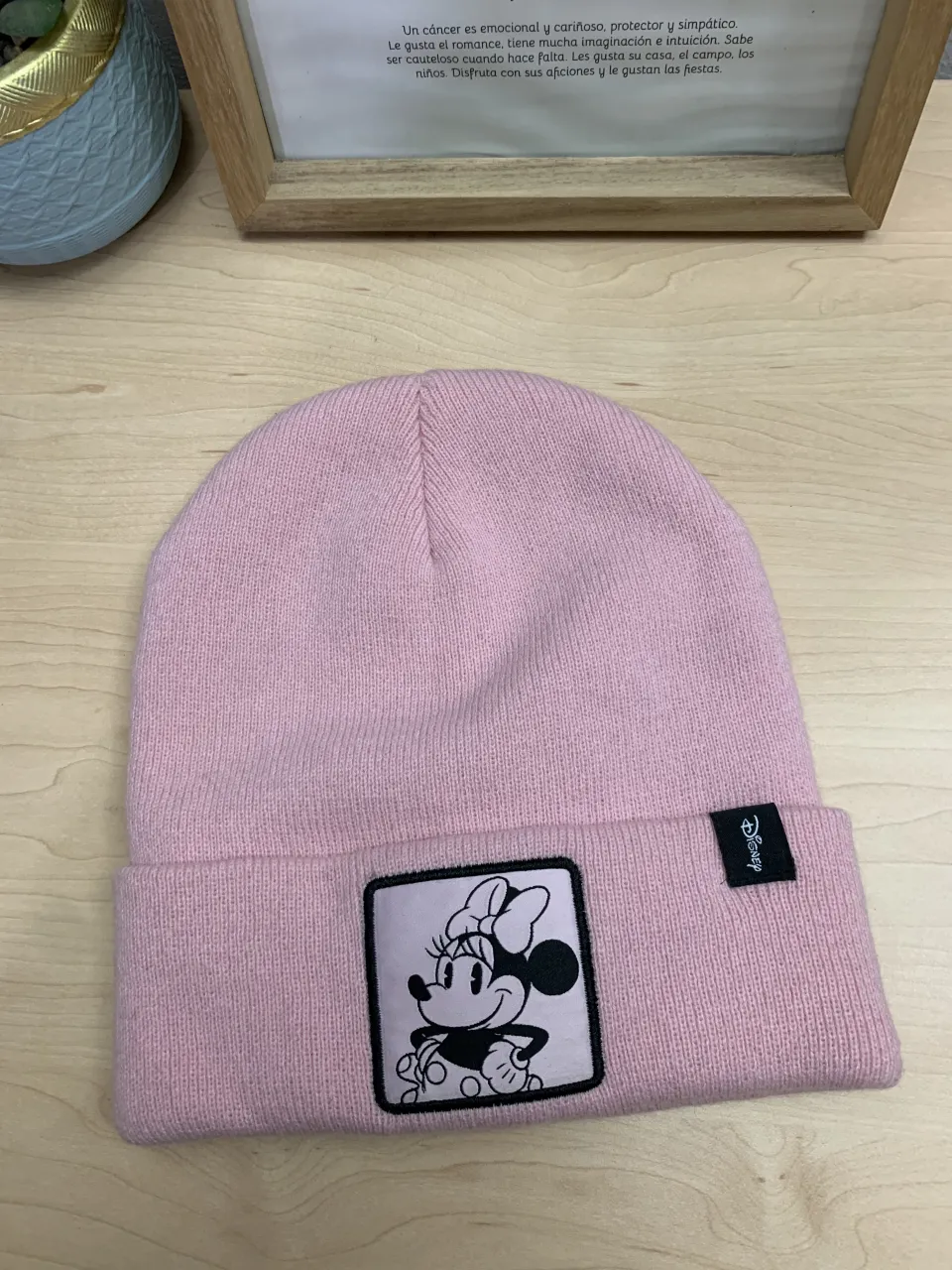 Gorro tejido de color rosa claro con un parche de Minnie Mouse en el frente y una etiqueta negra con el logo de Disney.