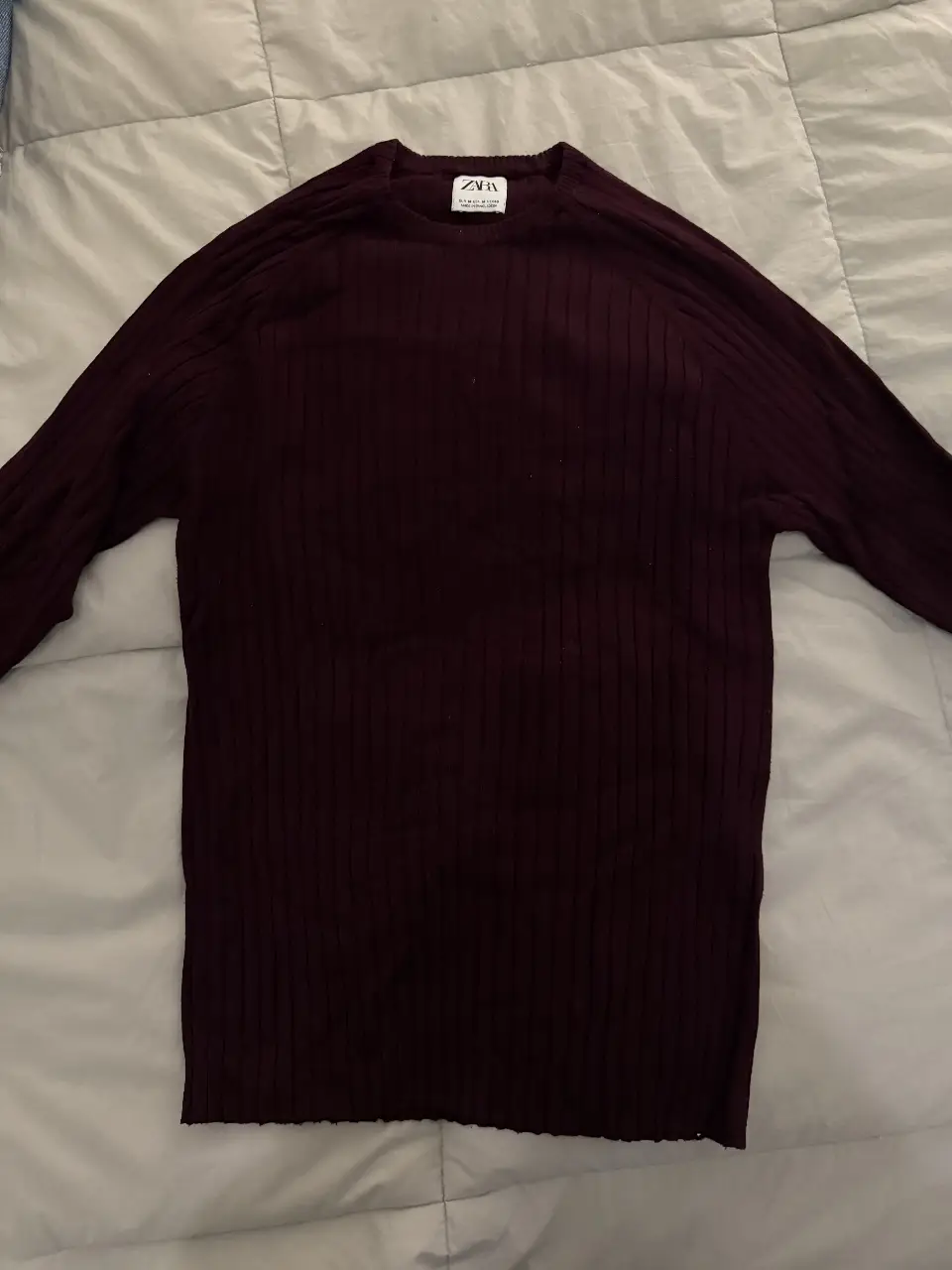 Sweater de cuello redondo de la marca Zara, color bordo, ideal para el invierno. Confeccionado en tejido de punto acanalado, este sweater ofrece un ajuste cómodo y un estilo versátil para cualquier ocasión.