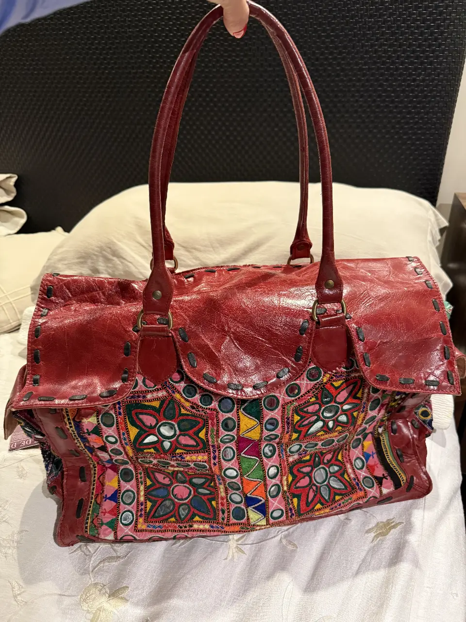 Cartera de cuero roja con detalles bordados y espejos. Estilo boho, ideal para un look artesanal y único. Amplia y con manijas para llevar al hombro.