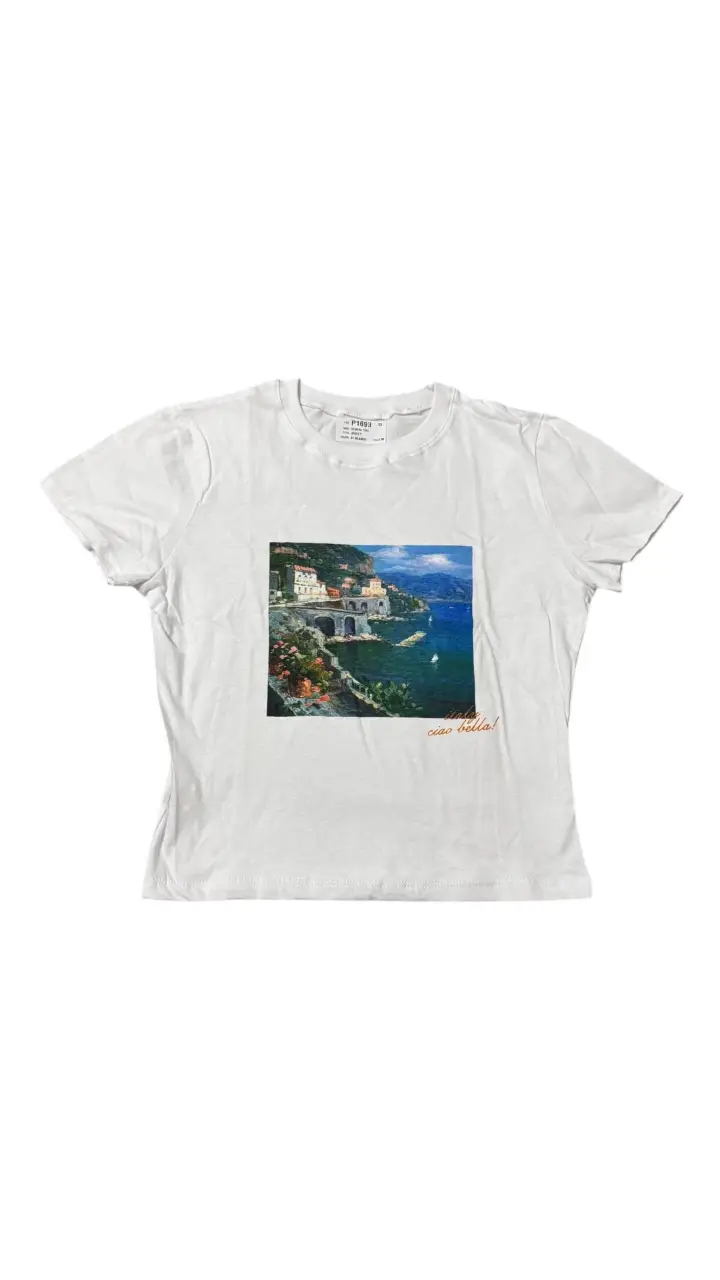 Remera blanca con estampado de paisaje costero italiano y la frase "ciao bella!". Ideal para un look casual y fresco.