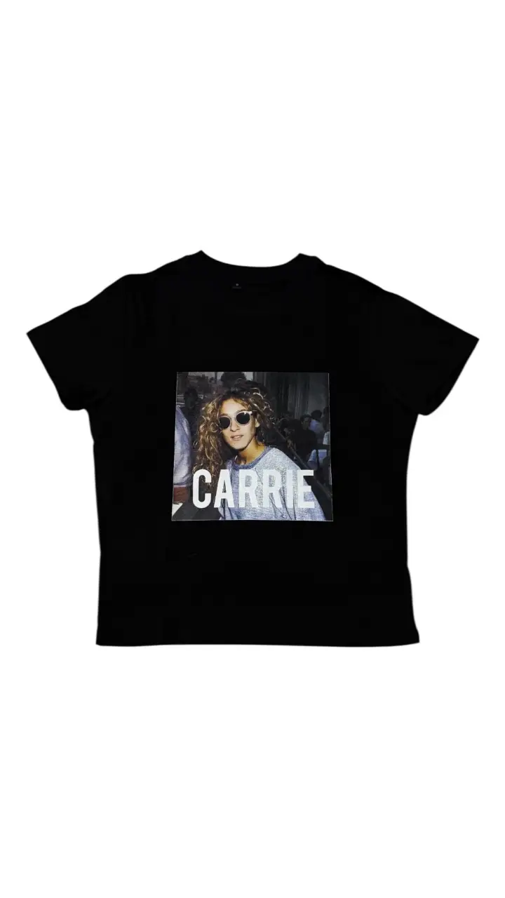 Remera negra con estampado de la actriz Carrie Bradshaw, ideal para un look casual y con onda. Perfecta para fans de Sex and the City.