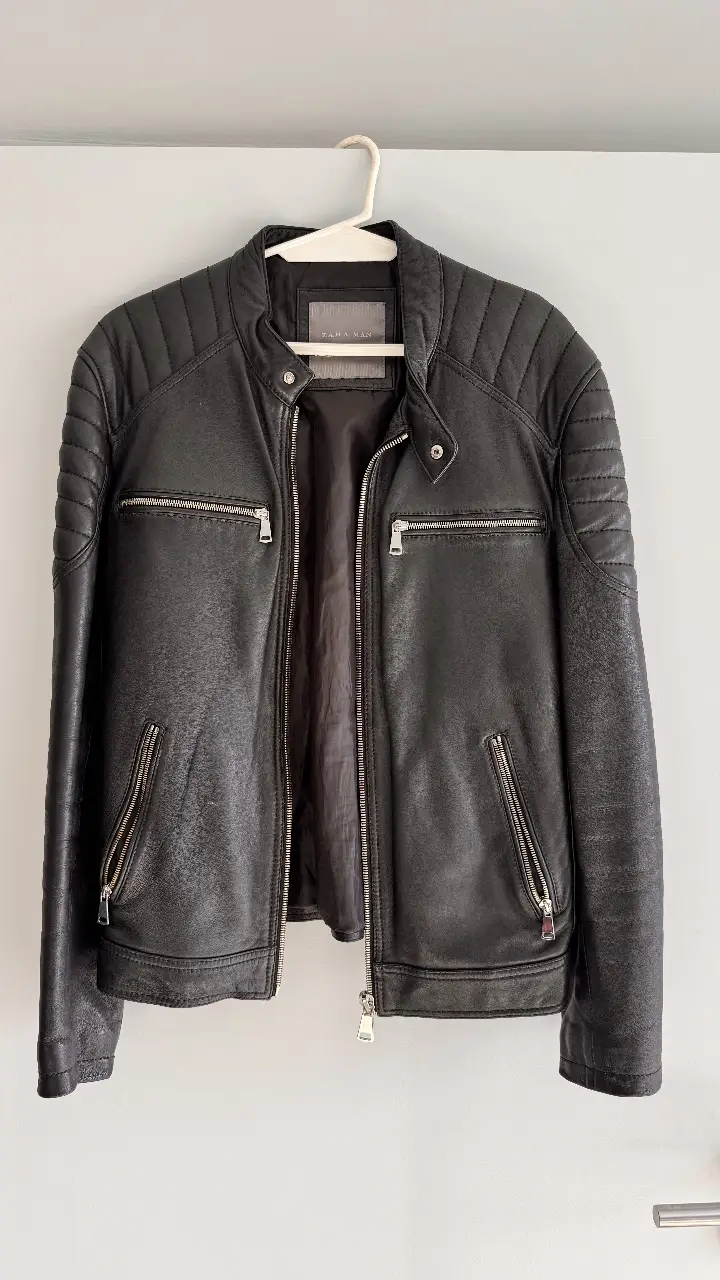 Campera biker de cuero Zara  para hombre, color negro. Con detalles acolchados en los hombros y mangas, cierre frontal y bolsillos con cierre. Ideal para un look moderno y urbano.