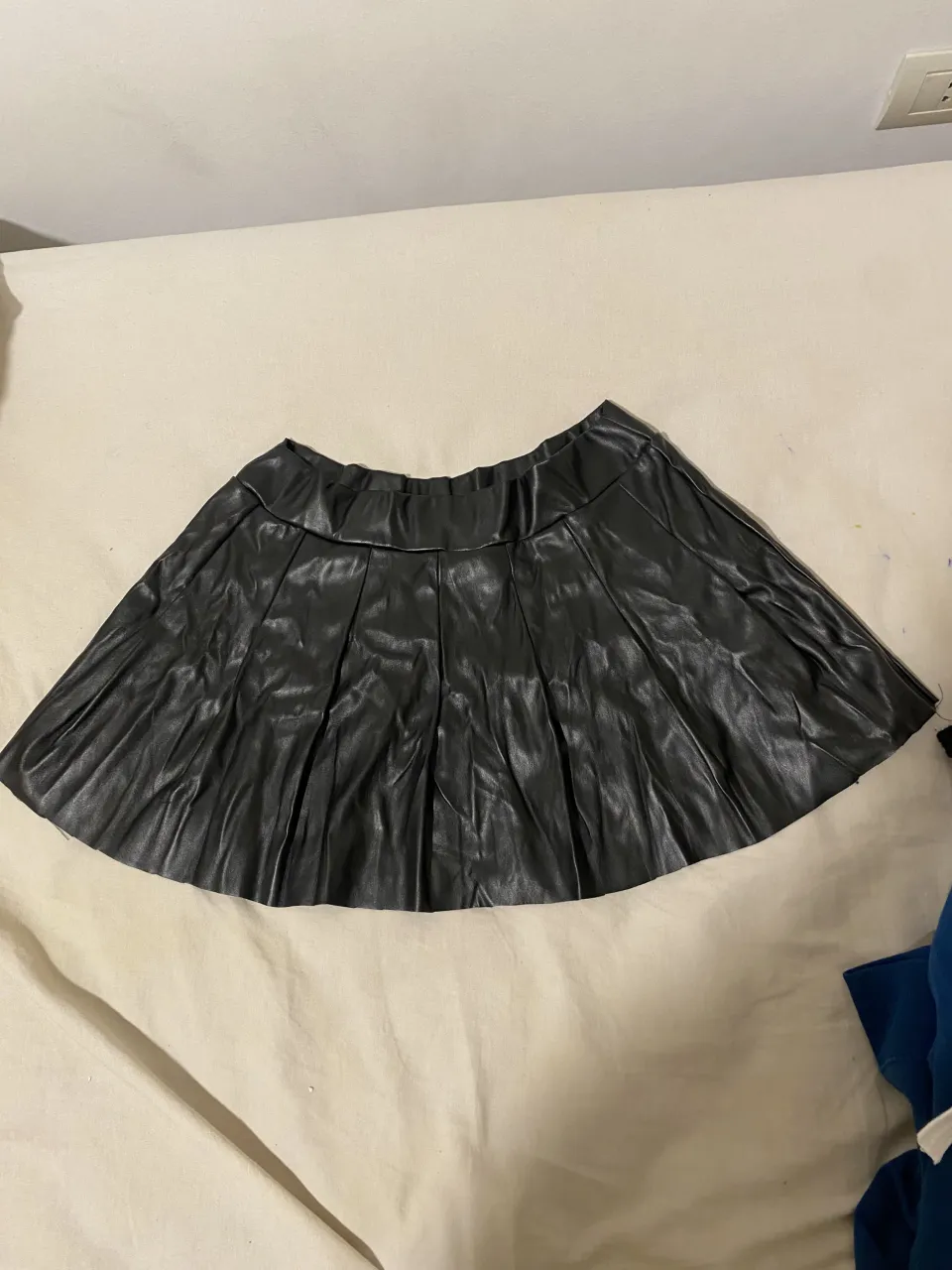 Pollera negra de cuero sintético, con tablas y cintura elastizada.