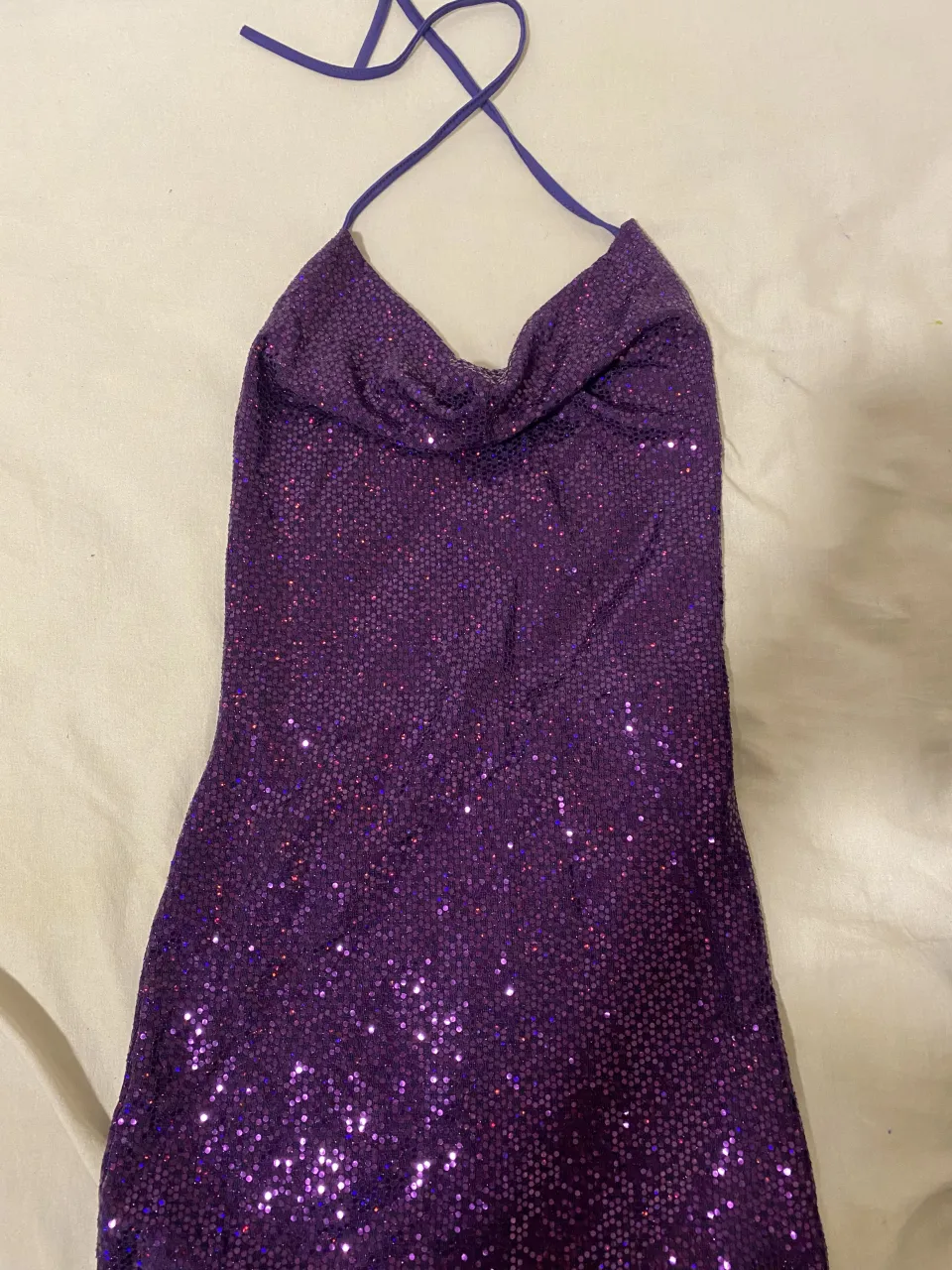 Vestido corto morado con lentejuelas y tiras finas para atar en la espalda.