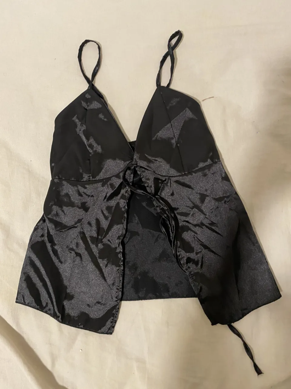 Top negro con tiras finas y escote en V. Posee un lazo para atar en la parte delantera.