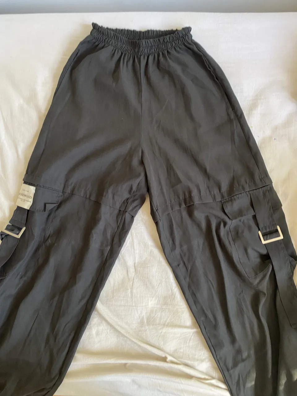 Pantalón cargo negro con hebillas plateadas y bolsillos laterales. Etiqueta interna con inscripción "ROSEWOOD MADE IN BUENOS AIRES, ARGENTINA Since 2017."