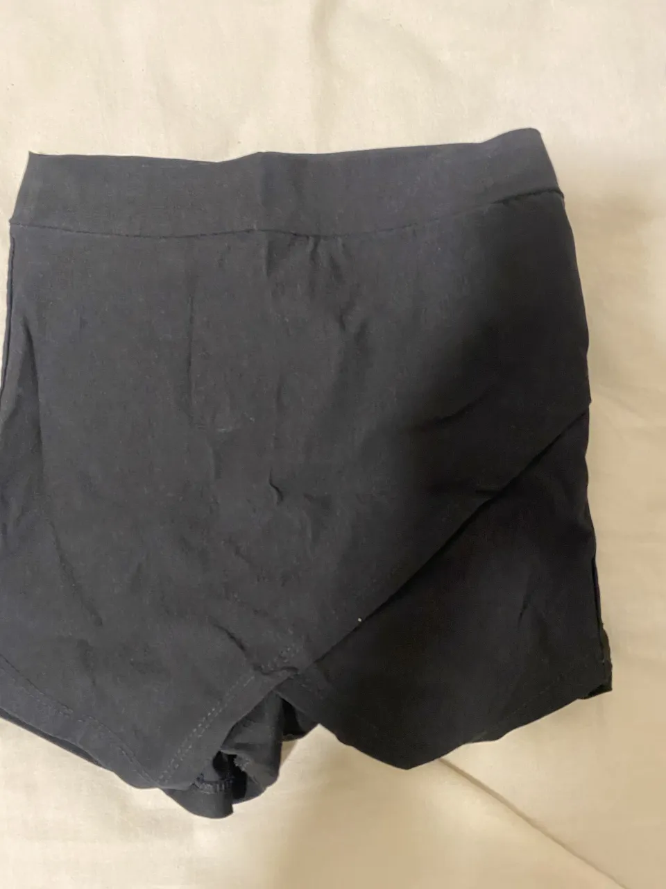 Pollera negra.  diseño cruzado en la parte delantera. Incluye shorts